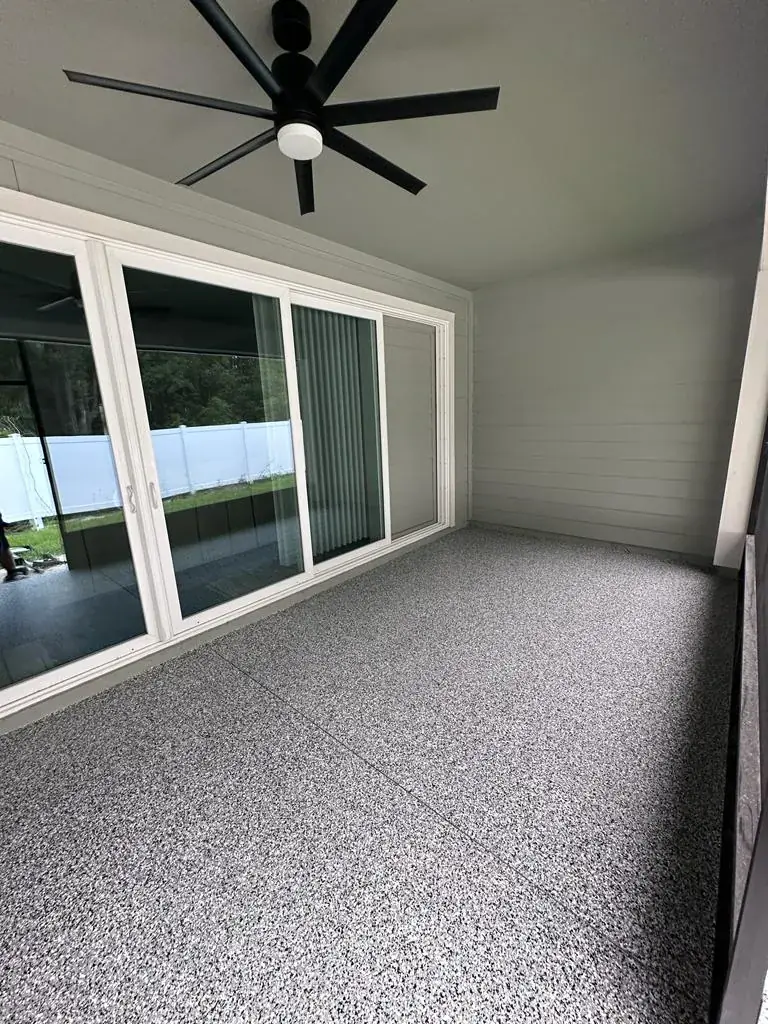 Covered lanai with a gray and black flake floor coating beside sliding glass doors