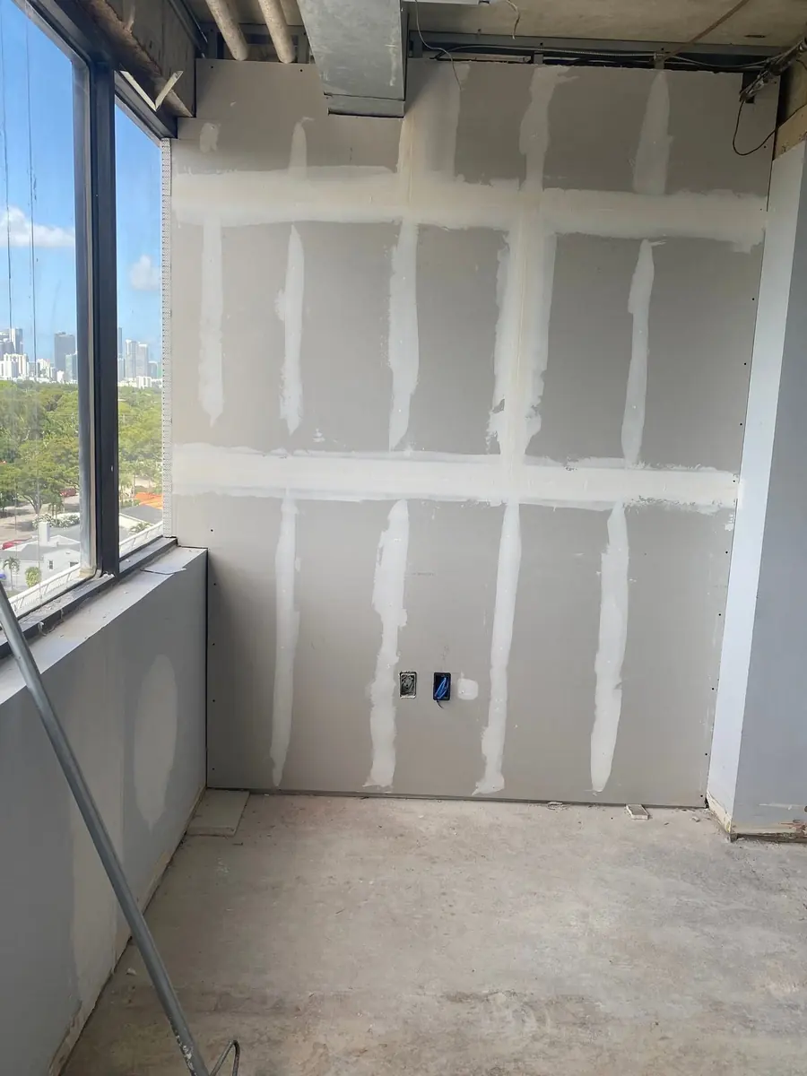 Office wall with drywall seams taped and mudded beside a window