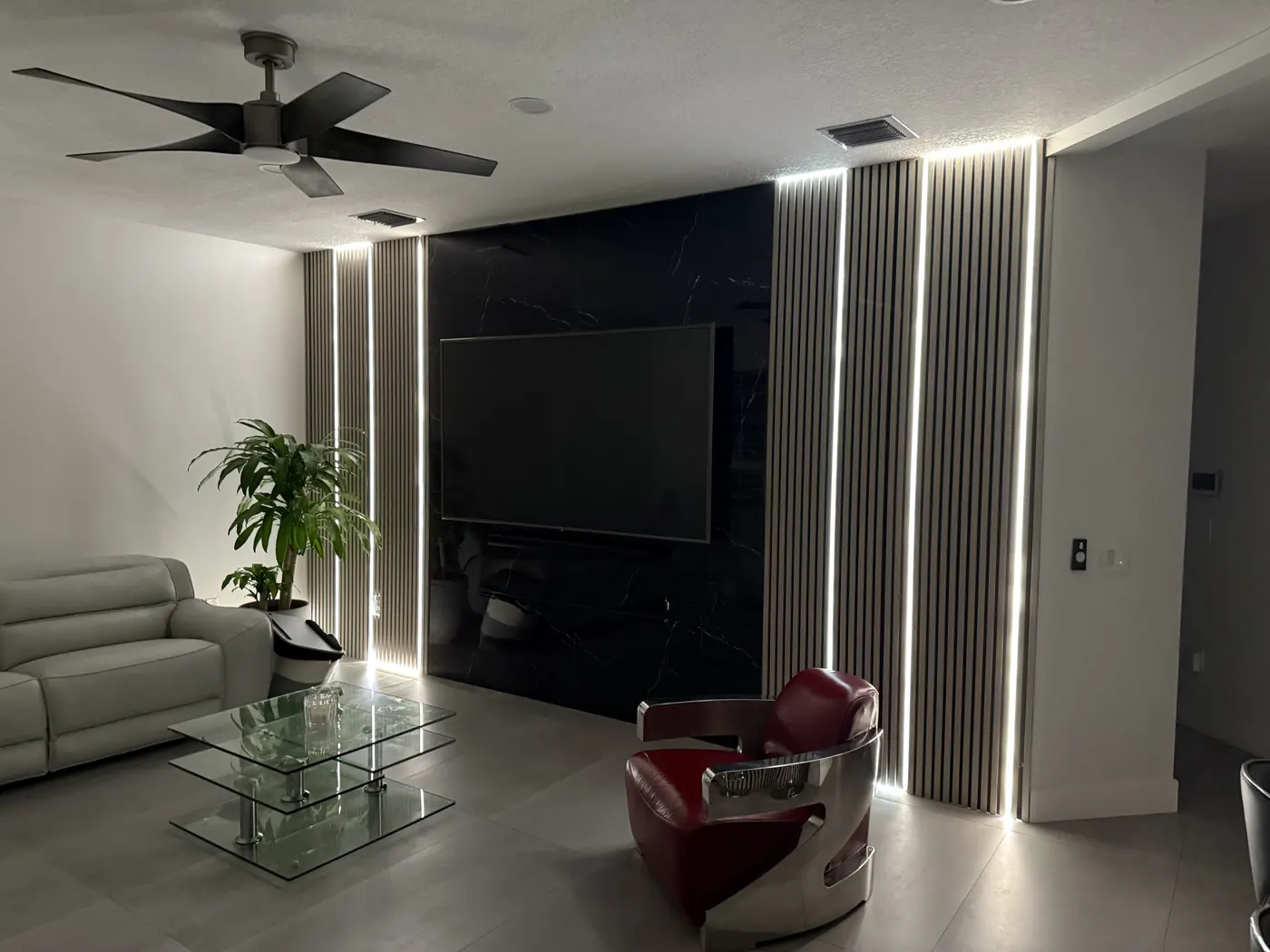 The finished feature wall at night, with LED strip lighting glowing between the wood slat panels