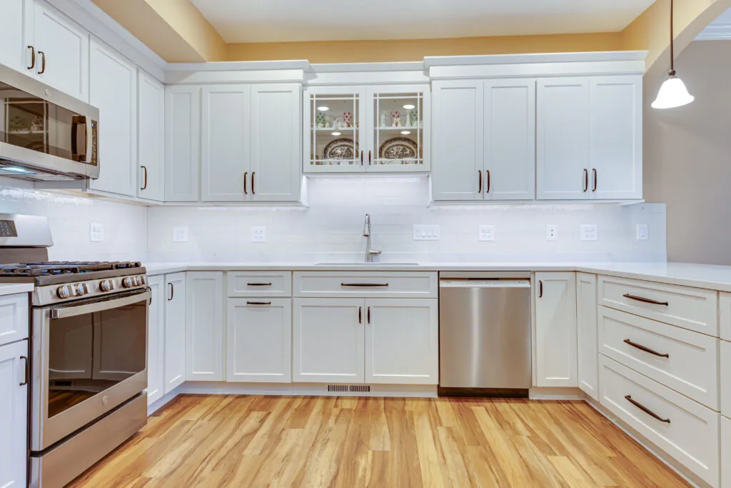 Kitchen after renovation: white shaker cabinets, quartz countertops, subway tile backsplash and new flooring
