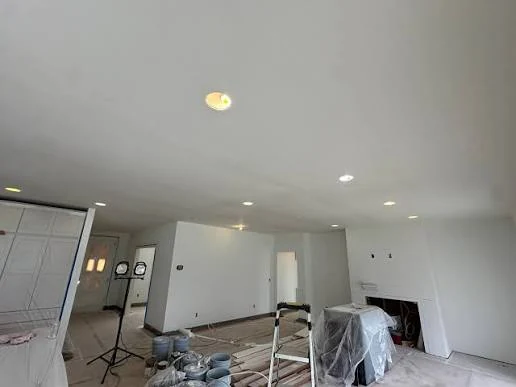 Open living area during an interior renovation, with new drywall, recessed lighting and freshly painted walls