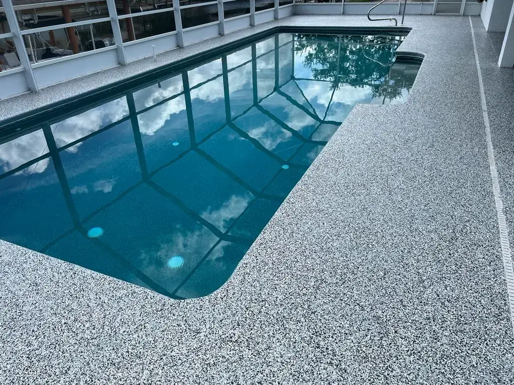 Pool deck with a white, gray and black flake coating inside a screened pool enclosure