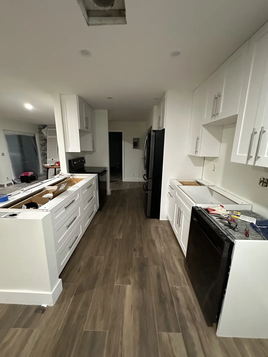 Galley kitchen with white shaker cabinets, bar pulls and new appliances installed, ready for quartz countertops