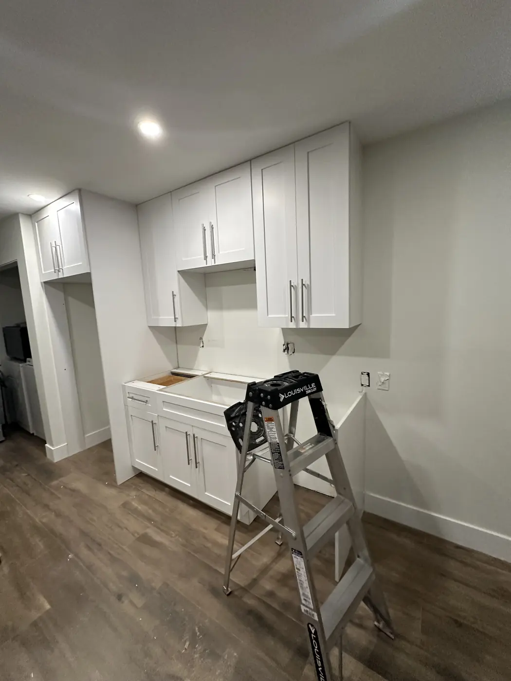White shaker wall cabinets with stainless bar pulls installed above the sink base